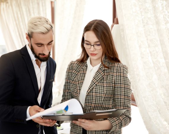 Two professionals in business attire examining a document, representing expert planning for custom birthday and wedding events.