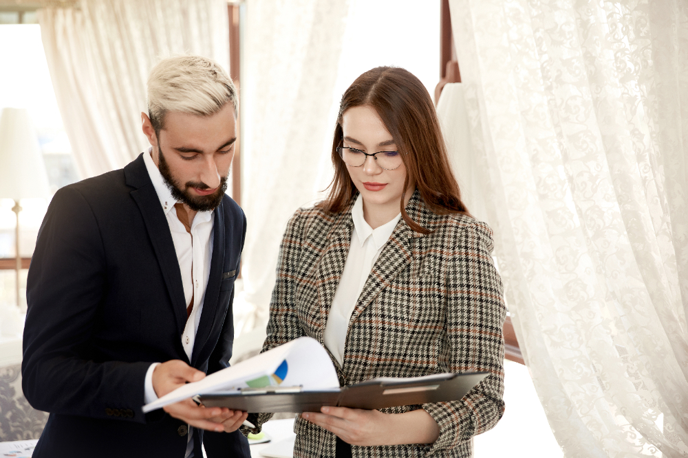 Two professionals in business attire examining a document, representing expert planning for custom birthday and wedding events.