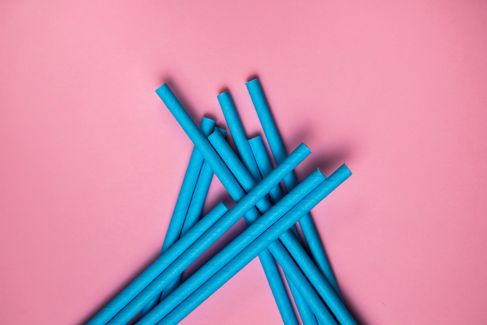 Blue plastic straws arranged on a pink background, promoting sustainable choices for the modern household.