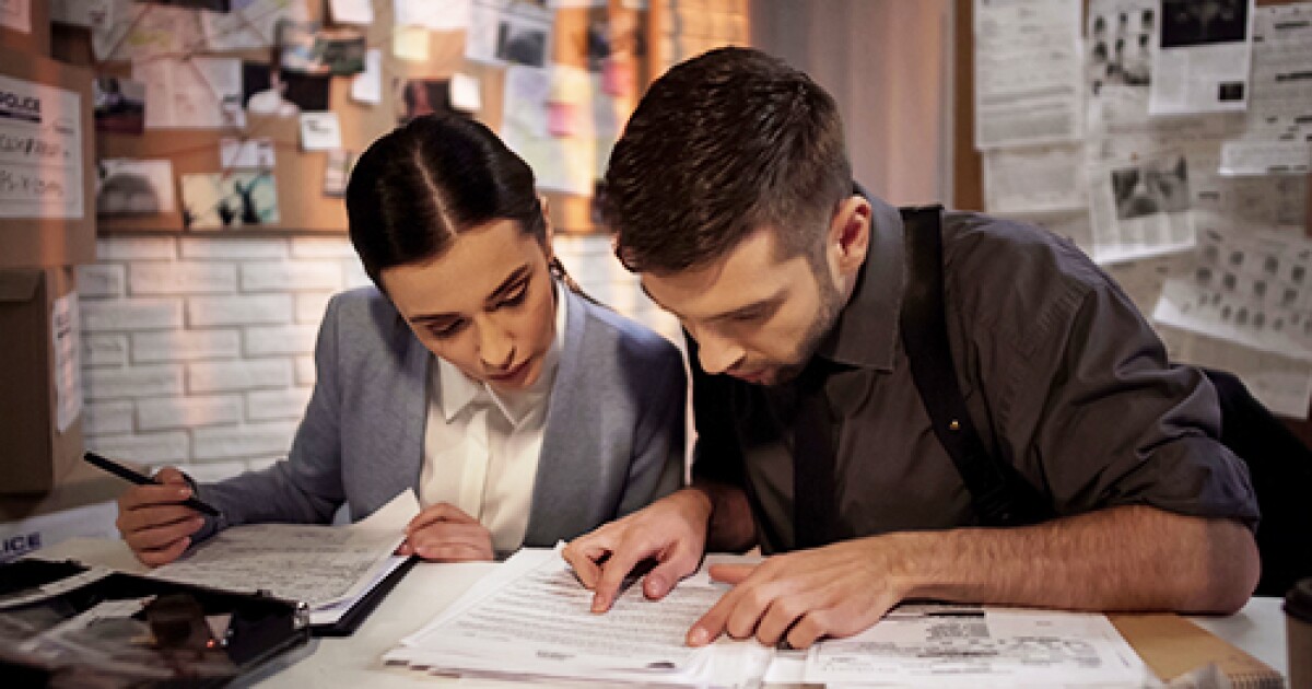 A man and woman diligently work on paperwork at a desk, representing reliable private investigators in criminal cases.