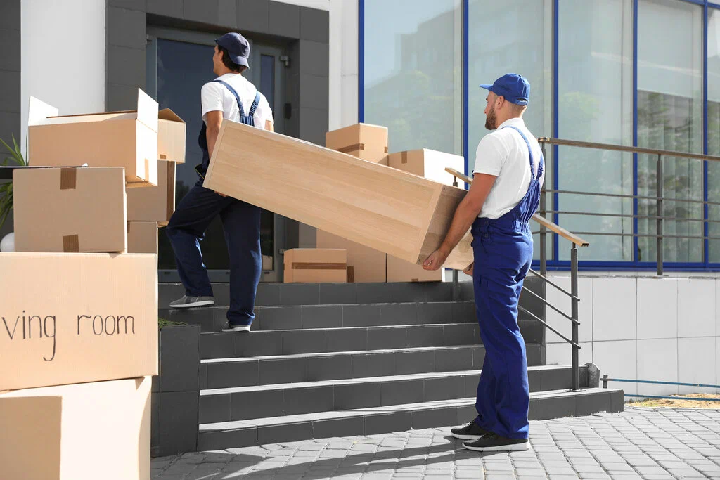 Two men ascend steps with boxes outside a building, illustrating the practicality of affordable moving services.