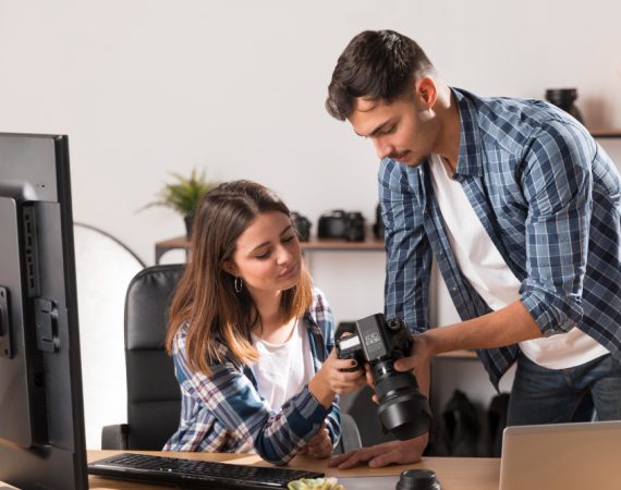 A man and woman focus on a computer, exploring options for liability insurance tailored for artisan contractors and photographers.