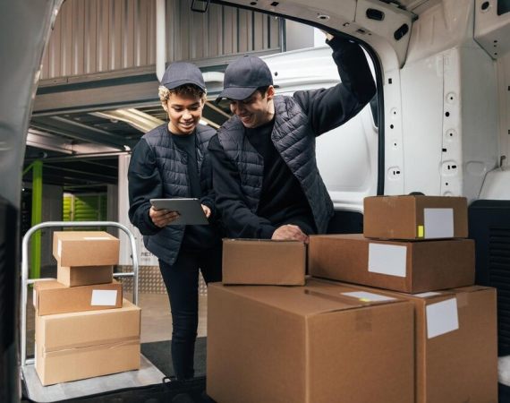 Two delivery workers organizing packages in a van, ensuring reliable transportation service.